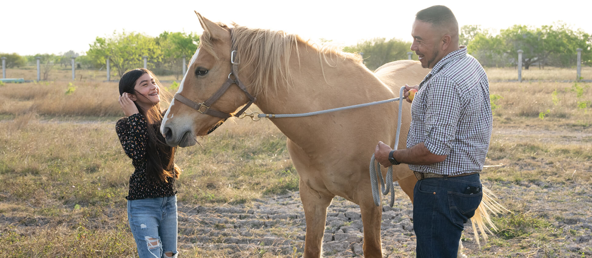 Father and daughter outside with a horse on a sunny day