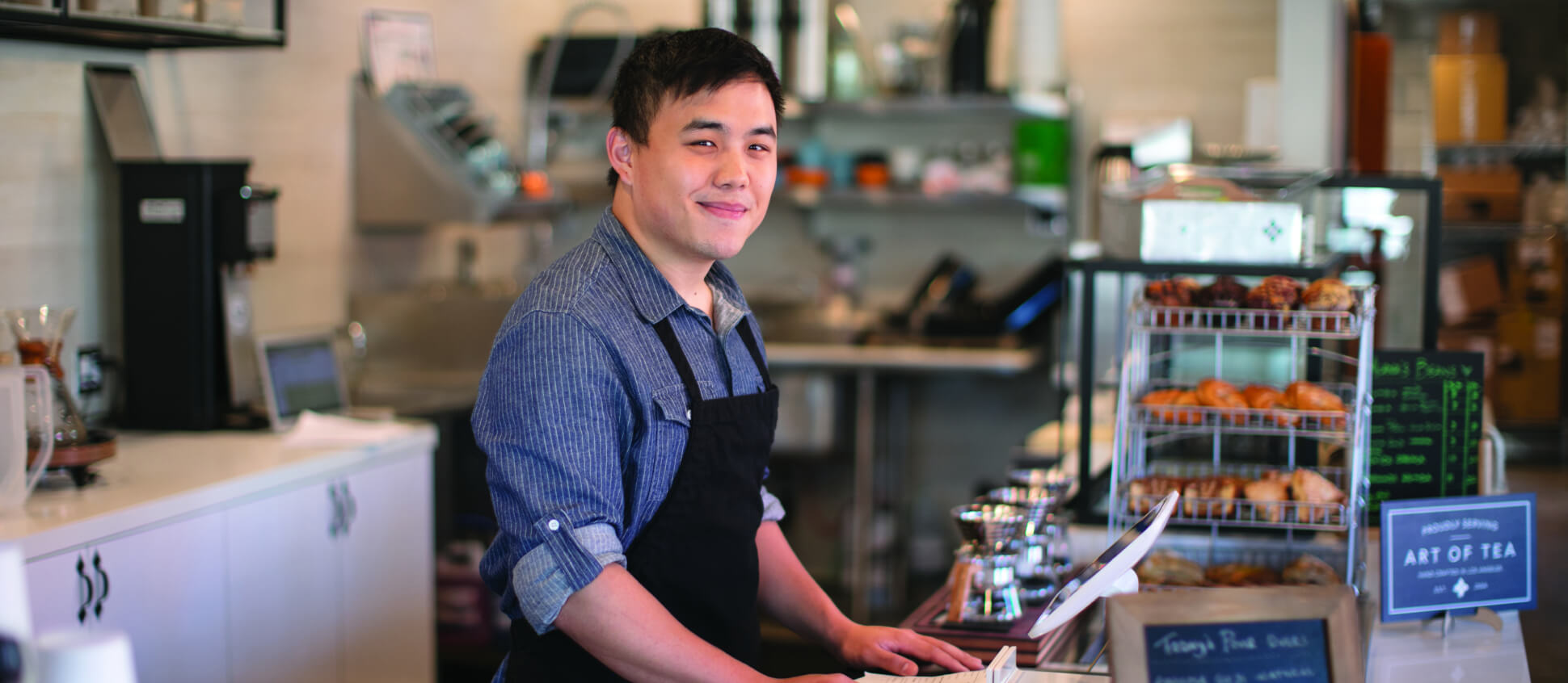 A barista standing at the register counter looking to the camera