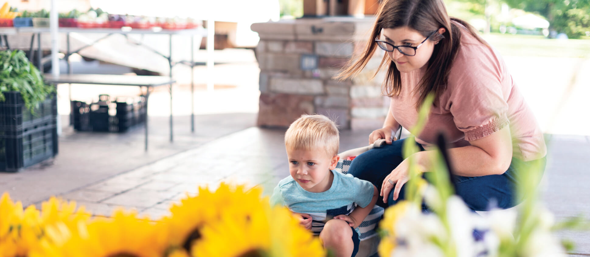 Woman and child at a farmers market looking at sunflowers