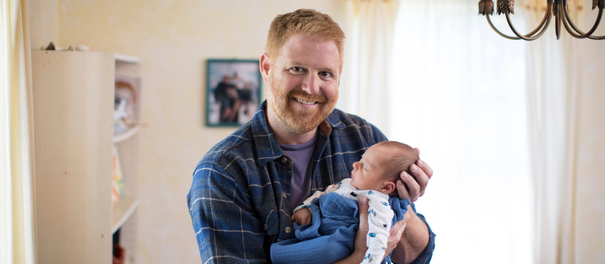 Father holding baby smiling at the camera