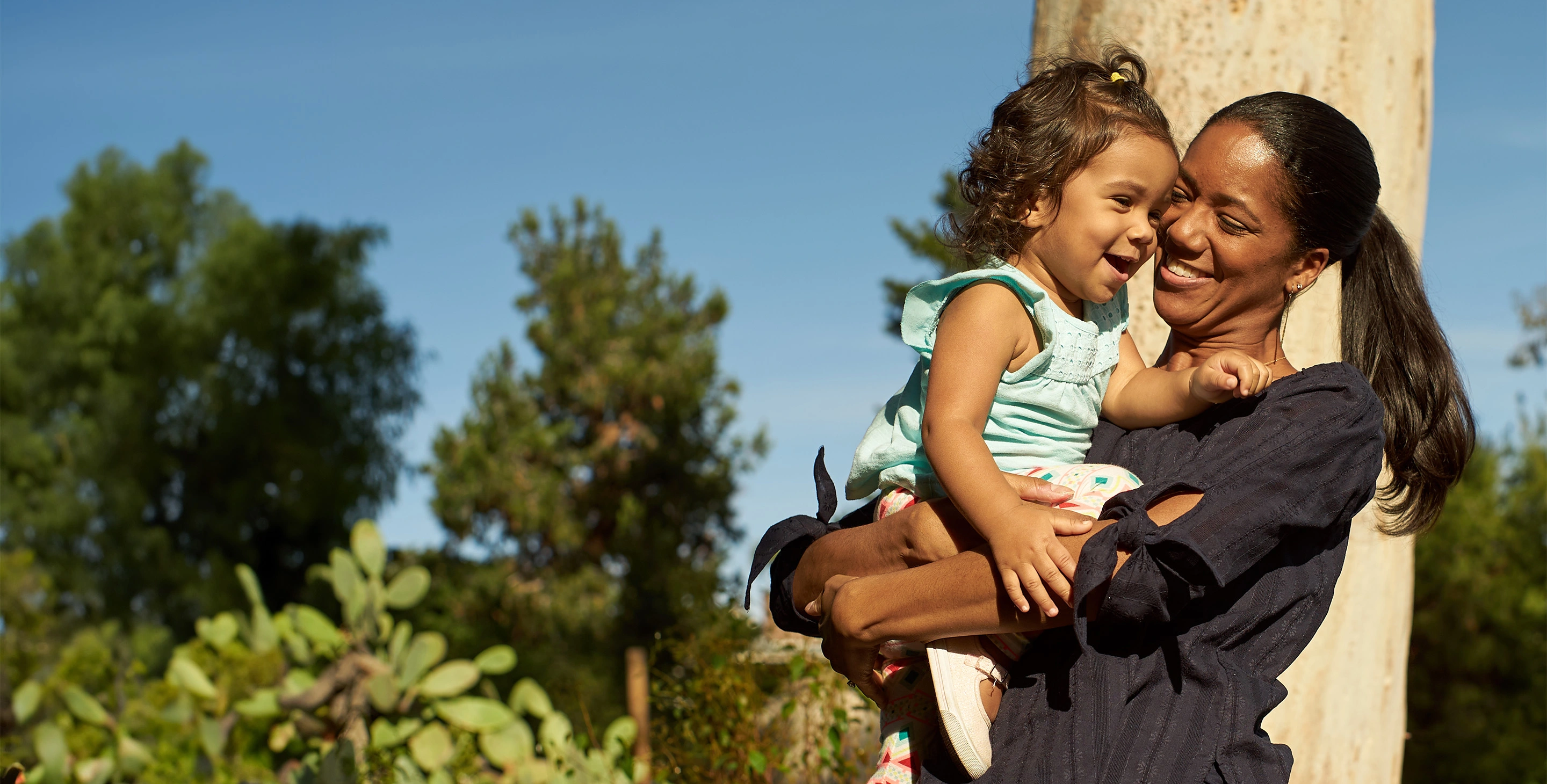 African American woman holding her smiling daughter in her arms.