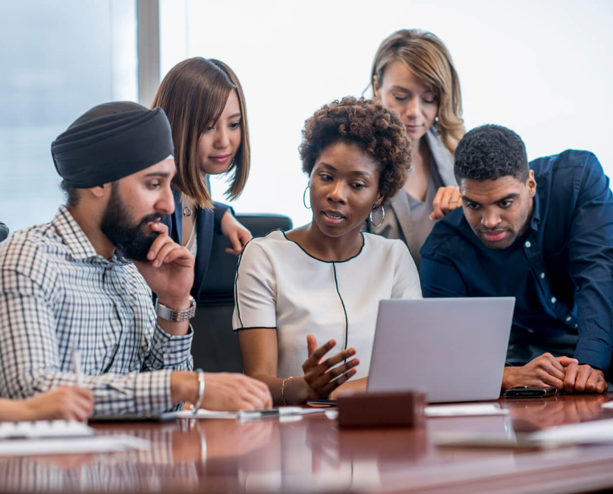 A group of business people looking at a laptop in a conference room.