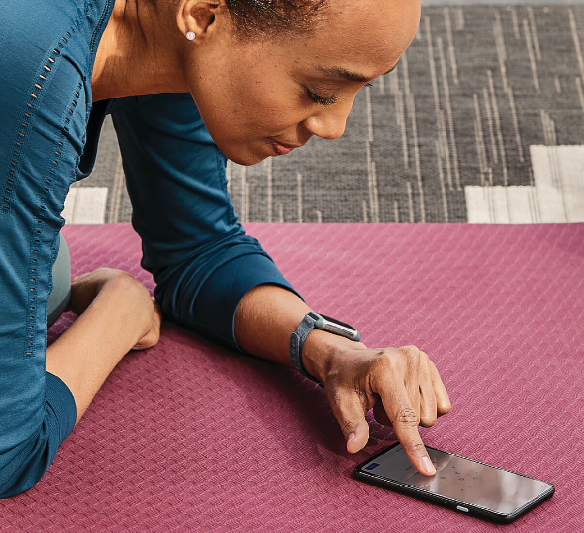 A woman looking at her phone on a yoga mat.