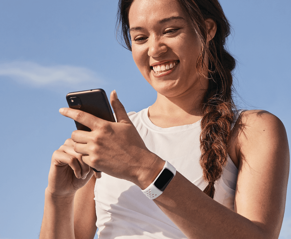 A woman holding a cell phone and smiling.