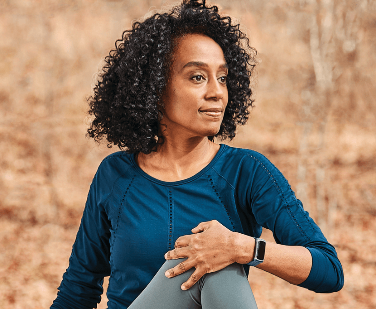 A woman with curly hair wearing a smartwatch device.